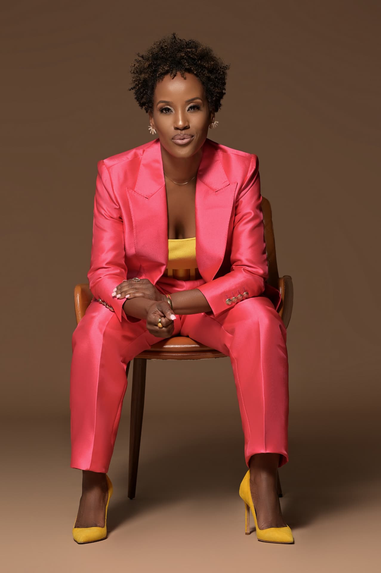 Megan Rivers seated brand portrait in a pink satin suit