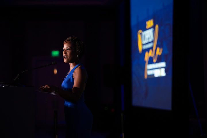 Megan Rivers speaking confidently at a podium on stage